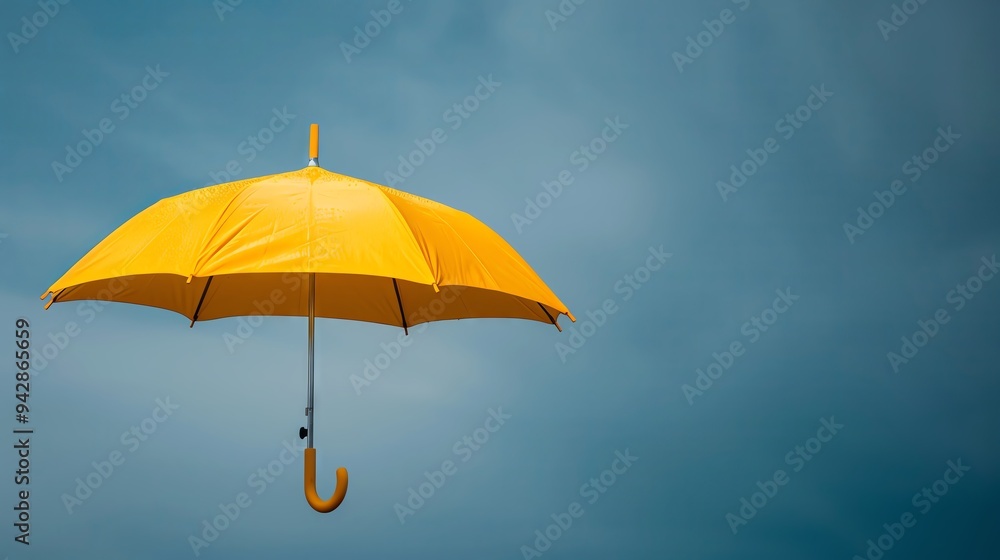 A bright yellow umbrella suspended against a moody blue sky, symbolizing protection and optimism in uncertain weather. A bright yellow umbrella suspended against a moody blue sky, symbolizing protection and optimism in uncertain weather.