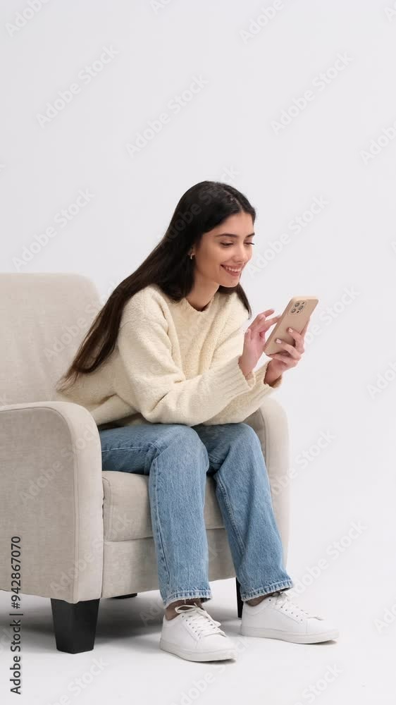 Joyful Caucasian young adult woman using mobile phone and laughing on white background. Concept of an online entertainment in cyberspace. Vertical video. Joyful Caucasian young adult woman using mobile phone and laughing on white background. Concept of an online entertainment in cyberspace. Vertical video.