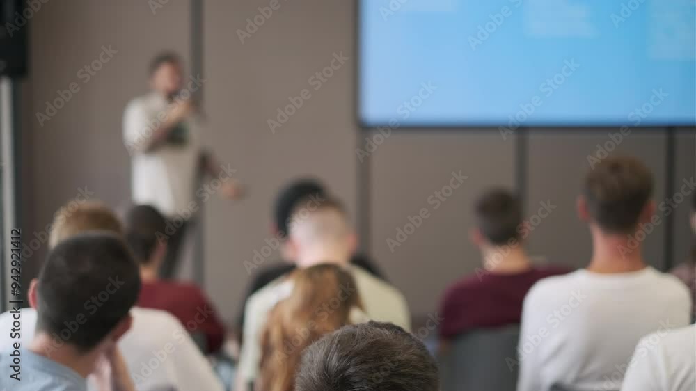 Speaker presents in front of a focused audience during a seminar. The setting is professional and conducive to learning and engagement. Speaker presents in front of a focused audience during a seminar. The setting is professional and conducive to learning and engagement.