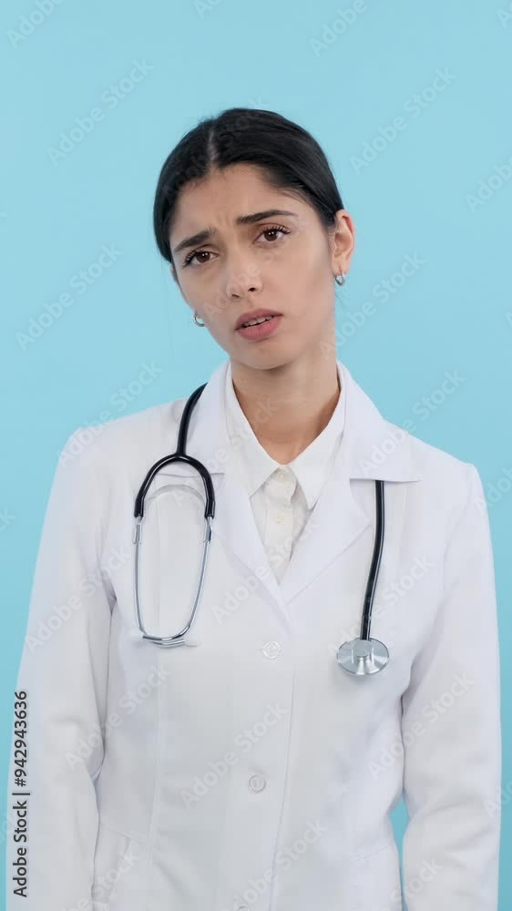 Caucasian female serious doctor or intern doing deep breath and getting be upset on blue background. Concept of a negative emotions. Vertical video. Caucasian female serious doctor or intern doing deep breath and getting be upset on blue background. Concept of a negative emotions. Vertical video.