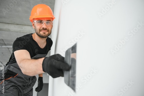 Tradesman on stilts plastering drywall in home