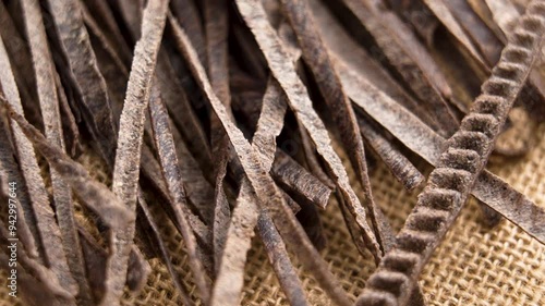 Organic black bean fettuccine pasta falling on a rough sack cloth. Uncooked gluten-free ingredient. Macro. Slow motion photo