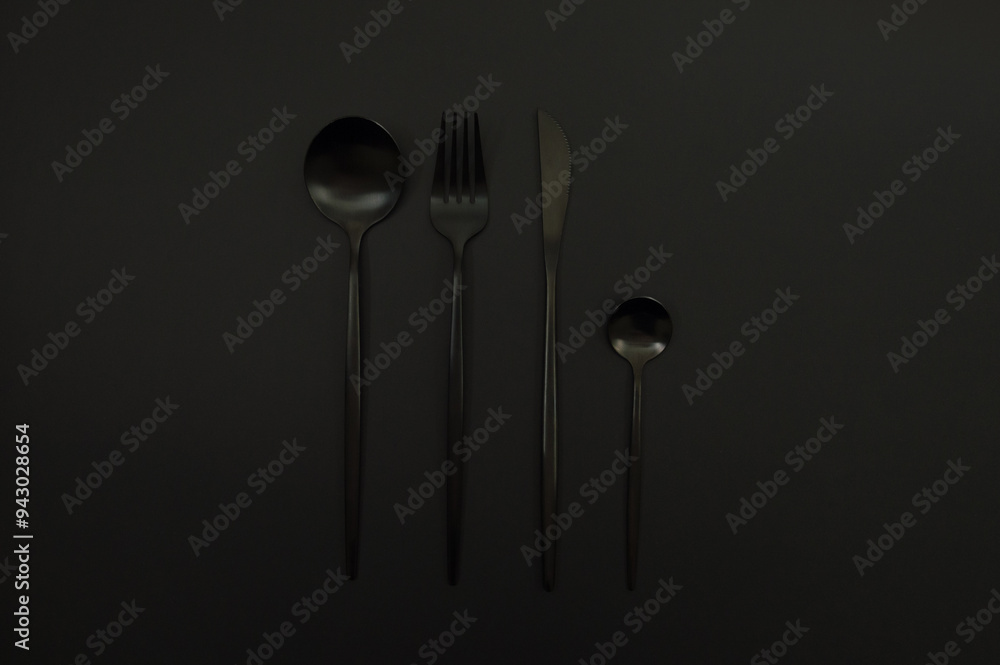 Top view of black cutlery on black background. Knife, fork, spoon and dessert spoon. Copy space, flat lay. Top view of black cutlery on black background. Knife, fork, spoon and dessert spoon. Copy space, flat lay.
