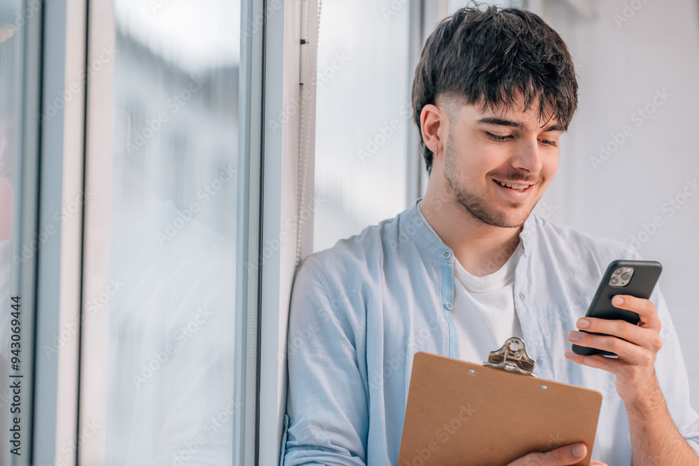 Fototapeta premium young man with mobile phone and documents next to the window