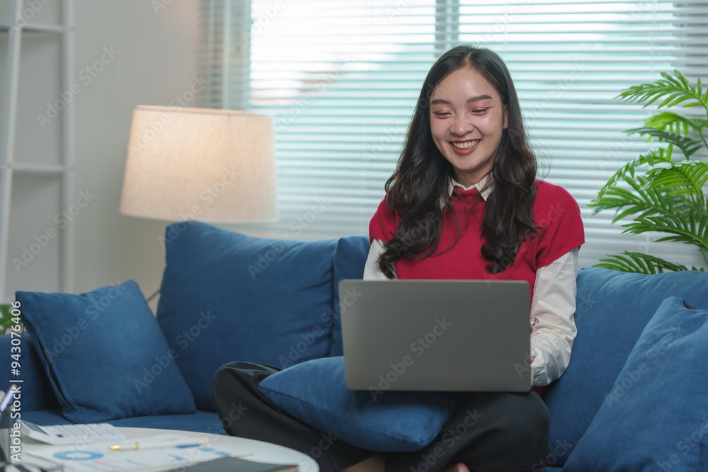 Beautiful young Asian woman sitting on sofa using laptop and calculator for homework, online work, learning, studying, thinking. Working concept startup business. Beautiful young Asian woman sitting on sofa using laptop and calculator for homework, online work, learning, studying, thinking. Working concept startup business.