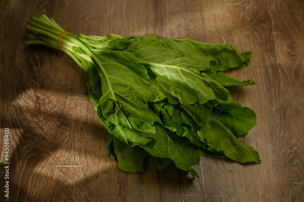 Spinach leaf on wooden background in rays of light Spinach leaf on wooden background in rays of light
