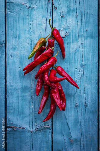 Color vertical photo, a bunch of red pounding hot chili peppers on a background of a blue wooden door.
