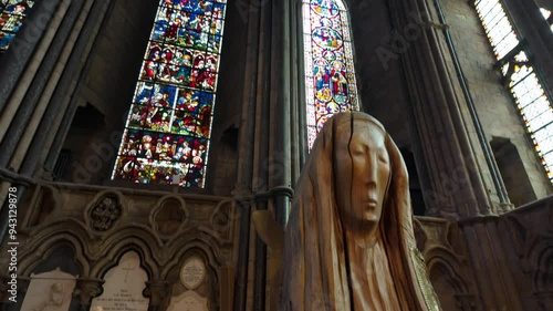 Camera tilts up to stained glass window of Durham Cathedral from modern statue in the Chapel of the Nine Alters 