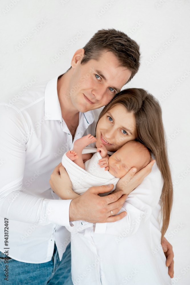 young parents with a newborn baby hug and kiss, happy mom and dad admiring the baby at home on the bed, a happy family caring for a small child, a place for text young parents with a newborn baby hug and kiss, happy mom and dad admiring the baby at home on the bed, a happy family caring for a small child, a place for text