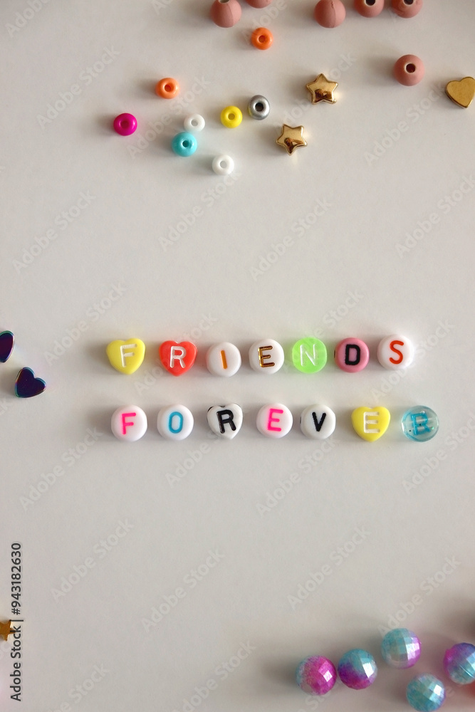 Friends forever written with colorful beads. Jewelry making supplies on the table. Making friendship bracelets concept. Flat lay.