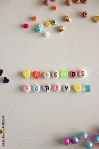 Obraz na płótnie Friends forever written with colorful beads. Jewelry making supplies on the table. Making friendship bracelets concept. Flat lay. w salonie