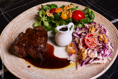 Filetto di manzo con cottura al sangue servito in un ristorante elegante con la riduzione della sua salsa, insalata verde e insalata di cavolo come contorno photo