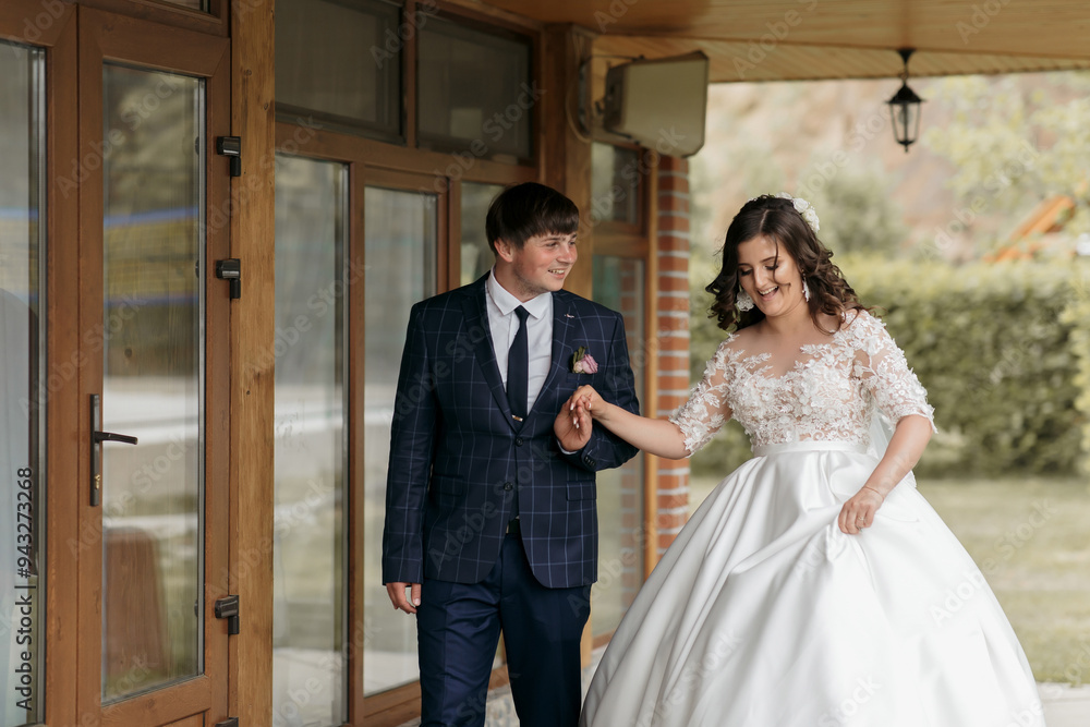 A bride and groom are walking down a hallway in a wedding dress and suit A bride and groom are walking down a hallway in a wedding dress and suit