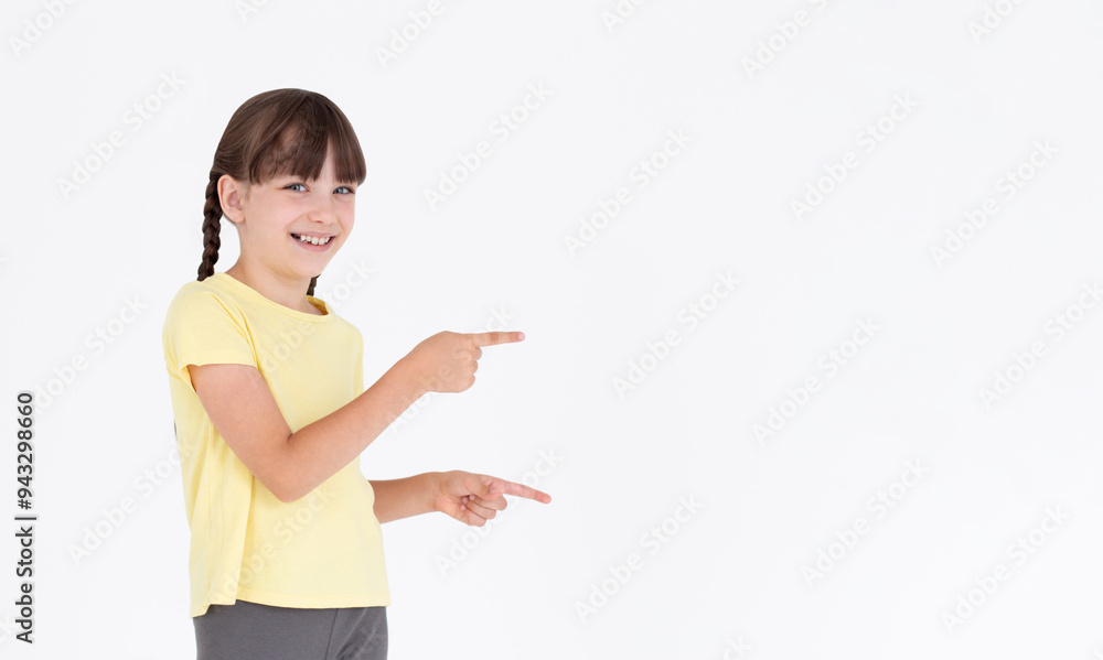 Portrait of smiling cute little kid girl pointing index finger up on mock up copy space for advertisement, posing isolated over white background wall in studio. Childhood lifestyle concept Portrait of smiling cute little kid girl pointing index finger up on mock up copy space for advertisement, posing isolated over white background wall in studio. Childhood lifestyle concept