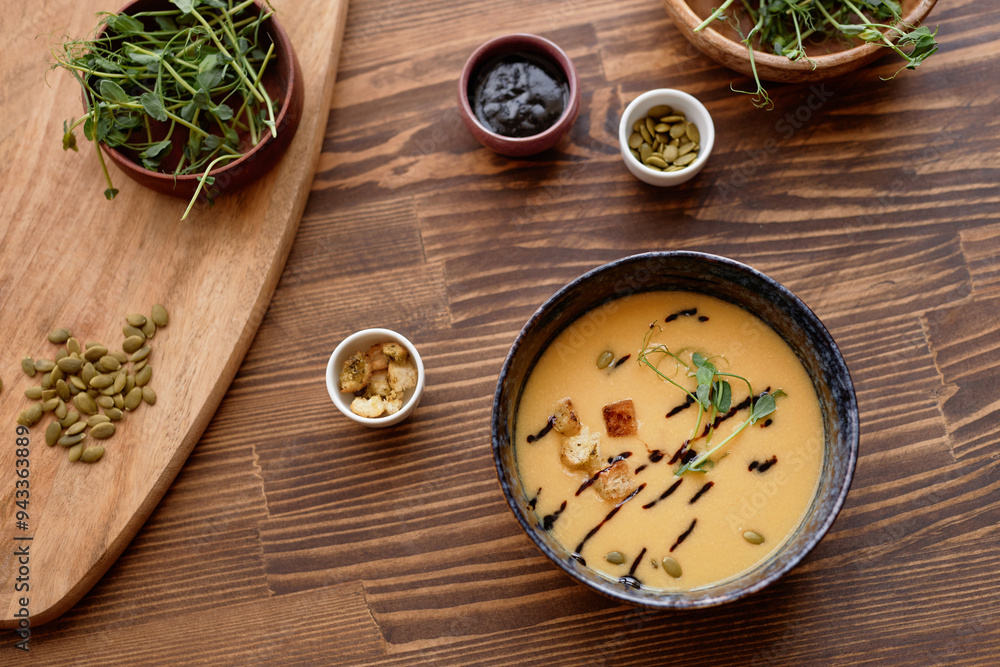 Top view background image of delicious hearty cream soup with cheese and crumble decorated with different add ons and sauce on wooden table Top view background image of delicious hearty cream soup with cheese and crumble decorated with different add ons and sauce on wooden table