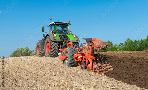 Tractor with 7-share reversible plow cultivating the field after the grain harvest - 2184 photo