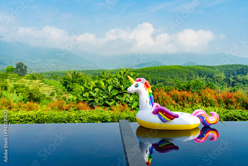 Unicorn swim tube on the swimming pool with garden and mountain background