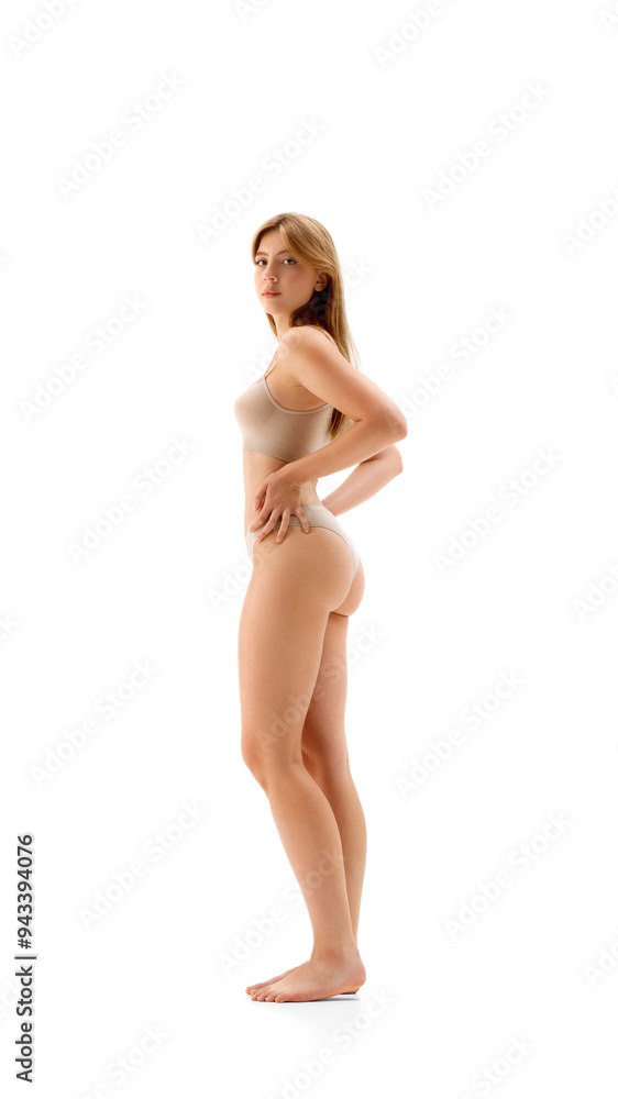 Full-length image of young beautiful woman with slim body posing in underwear isolated on white background. Side view. Sportive body. Concept of female beauty, body and skin care, cosmetology, health Full-length image of young beautiful woman with slim body posing in underwear isolated on white background. Side view. Sportive body. Concept of female beauty, body and skin care, cosmetology, health