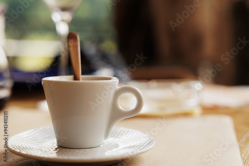 Obraz na płótnie tazzina bianca per caffè espresso al bar in primo piano, con all'interno un piccolo cucchiaio, su un tavolo, durante il giorno w salonie
