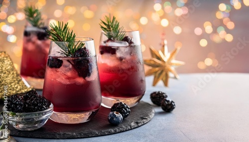 festive winter berry cocktails with blackberry liqueur and gin for christmas or new year celebration garnished with fresh berries