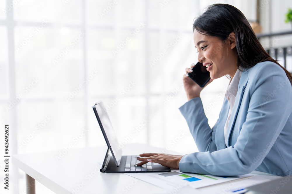 A woman is talking on her cell phone while sitting at a desk A woman is talking on her cell phone while sitting at a desk