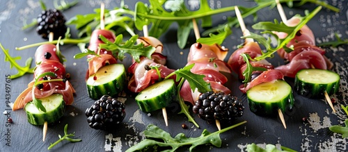 Party appetizers consisting of skewered prosciutto blackberries cucumber and arugula creating a colorful and tasty combination on a copy space image photo