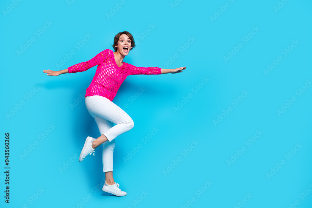 Full length photo of cheerful excited lady dressed pink knitted shirt flying dancing empty space isolated blue color background Full length photo of cheerful excited lady dressed pink knitted shirt flying dancing empty space isolated blue color background
