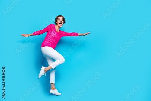 Full length photo of cheerful excited lady dressed pink knitted shirt flying dancing empty space isolated blue color background