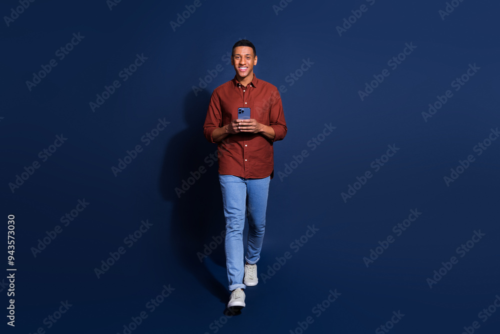 Full length photo of cheerful positive guy dressed brown shirt chatting modern device emtpy space isolated blue color background Full length photo of cheerful positive guy dressed brown shirt chatting modern device emtpy space isolated blue color background