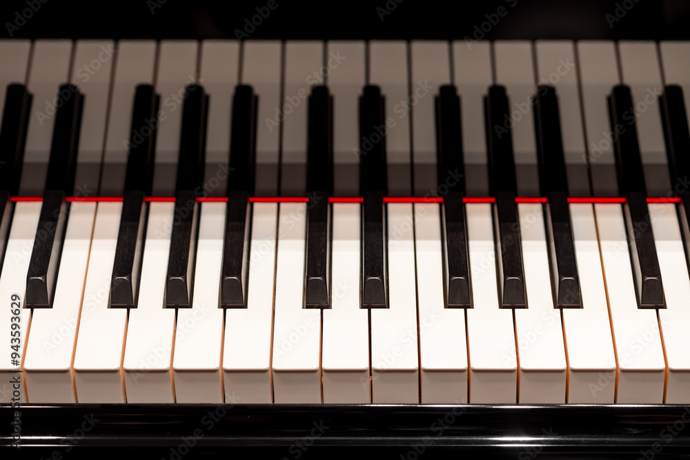 Keyboard of a grand piano in a concert hall with stage lighting. The black and white keys of the elegant musical instrument form a strong contrast and are reflected in the high-gloss lacquer. Keyboard of a grand piano in a concert hall with stage lighting. The black and white keys of the elegant musical instrument form a strong contrast and are reflected in the high-gloss lacquer.