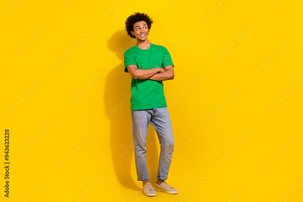Full length photo of funky cool guy dressed green t-shirt arms folded emtpy space isolated yellow color background Full length photo of funky cool guy dressed green t-shirt arms folded emtpy space isolated yellow color background