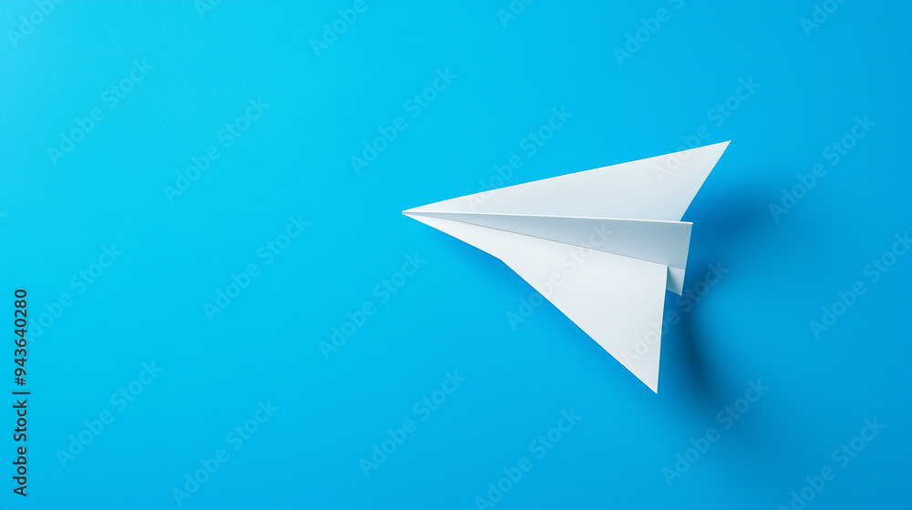 Top View Minimalist Paper Airplane. Top view of a white paper airplane on a blue background suggesting creativity and innovation. Top View Minimalist Paper Airplane. Top view of a white paper airplane on a blue background suggesting creativity and innovation.