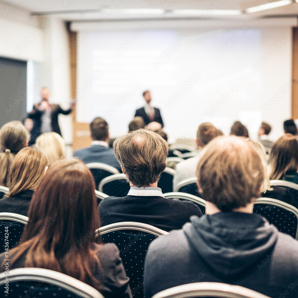Obraz premium Speaker giving a talk in conference hall at business event. Rear view of unrecognizable people in audience at the conference hall. Business and entrepreneurship concept