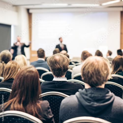 Speaker giving a talk in conference hall at business event. Rear view of unrecognizable people in audience at the conference hall. Business and entrepreneurship concept