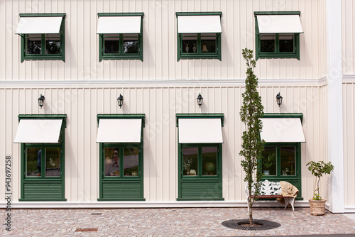 Grüne Fenster vor weißer Holzfassade. Skandinavische Architektur. Green windows in front of a white wooden façade. Scandinavian architecture.