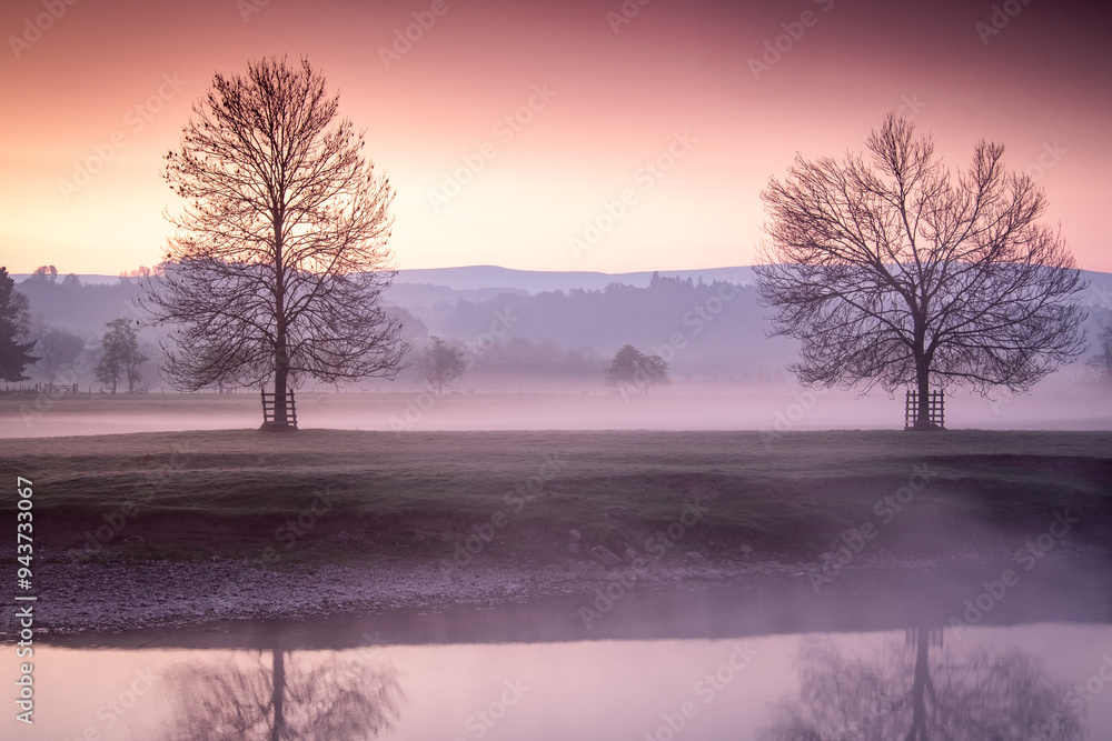 Sunrise over the river with mist flowing through the fields and trees Sunrise over the river with mist flowing through the fields and trees