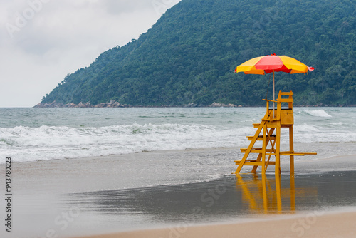 An empty lifeguard chair in front of a tourist beach that has strong waves. Tombo beach, Guaruja - SP- Brazil.