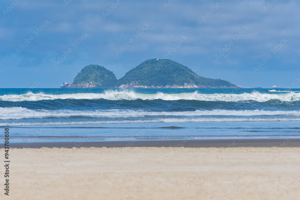 Morning at Enseada Beach on a beautiful day, view of the beach sand, the sea, and the Farol da Moela island on background. Guaruja - SP, Brazil. Morning at Enseada Beach on a beautiful day, view of the beach sand, the sea, and the Farol da Moela island on background. Guaruja - SP, Brazil.