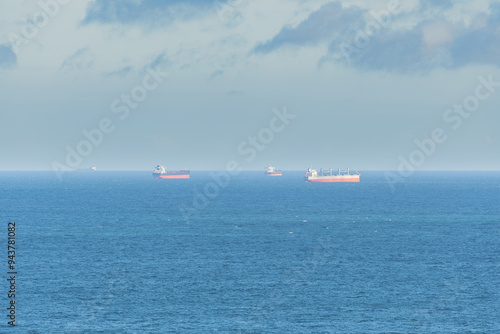 Cargo ships seen far away from the coast in the middle of the sea.
