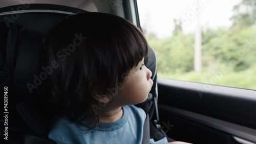 toddler girl sitting in a car seat and looking out of the window, safety baby chair travelling