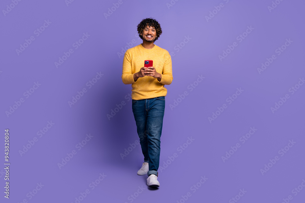 Photo of cheerful young man wear trendy yellow clothes hold use gadget isolated on purple color background Photo of cheerful young man wear trendy yellow clothes hold use gadget isolated on purple color background