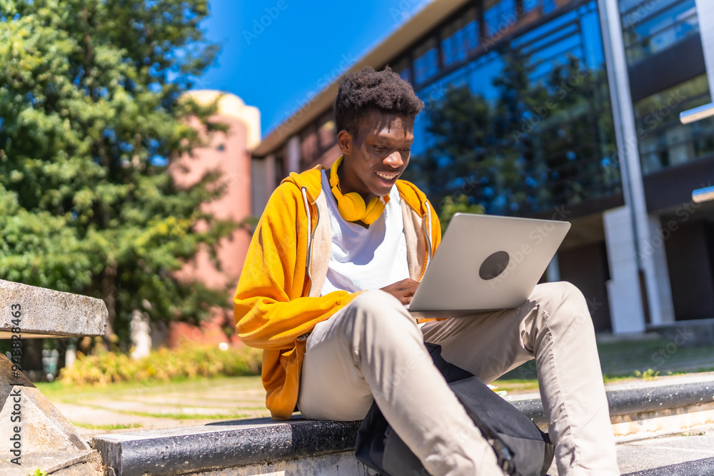 Fototapeta premium African man sitting at campus studying using laptop