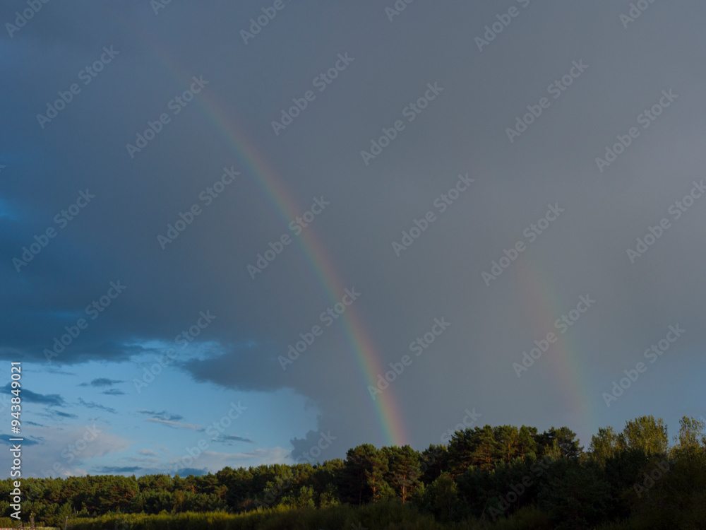 Amid dark clouds, a brilliant rainbow emerges, its colors vivid against the stormy backdrop. As the rainbow stretches across the sky, the contrast with the clouds enhances the scene's dramatic beauty. Amid dark clouds, a brilliant rainbow emerges, its colors vivid against the stormy backdrop. As the rainbow stretches across the sky, the contrast with the clouds enhances the scene's dramatic beauty.