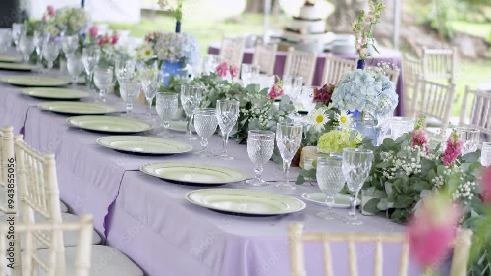 Long banquet table with purple tablecloth and glassware at outdoor wedding reception. Floral decoration. Long banquet table with purple tablecloth and glassware at outdoor wedding reception. Floral decoration.