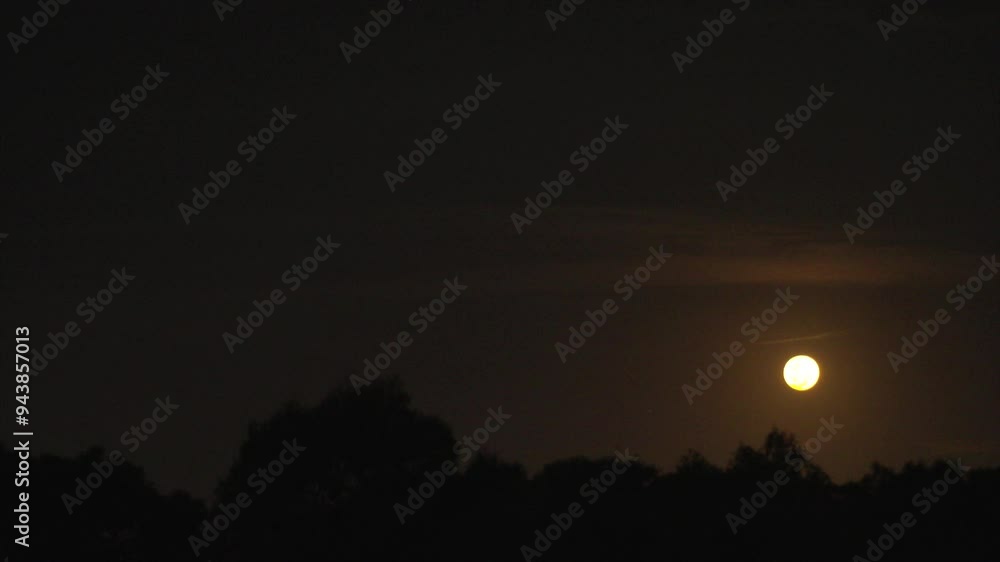 A glowing golden moon rising in the dark sky A glowing golden moon rising in the dark sky