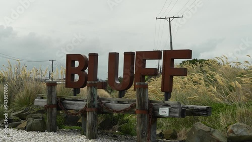 Rusty metal Bluff town sign on gorund coverd with fmaous bluff oysters with long grass. photo