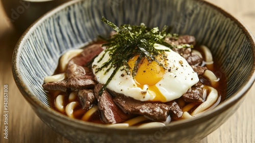 Mouthwatering udon noodle dish featuring beef, poached egg, and seaweed, served in a beautifully crafted ceramic bowl. photo