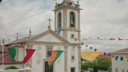 church adorned with colorful flags under a cloudy sky during festive event photo