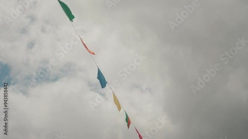 Colorful string flags fluttering in the wind against a cloudy sky photo