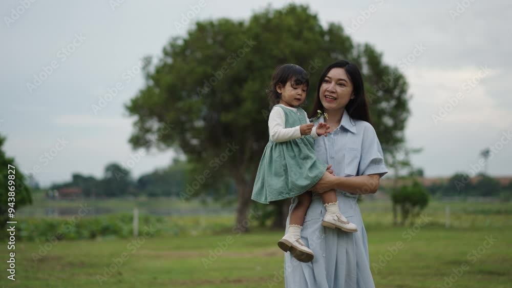 happy mother walking with her toddler baby girl on grass field in the park happy mother walking with her toddler baby girl on grass field in the park